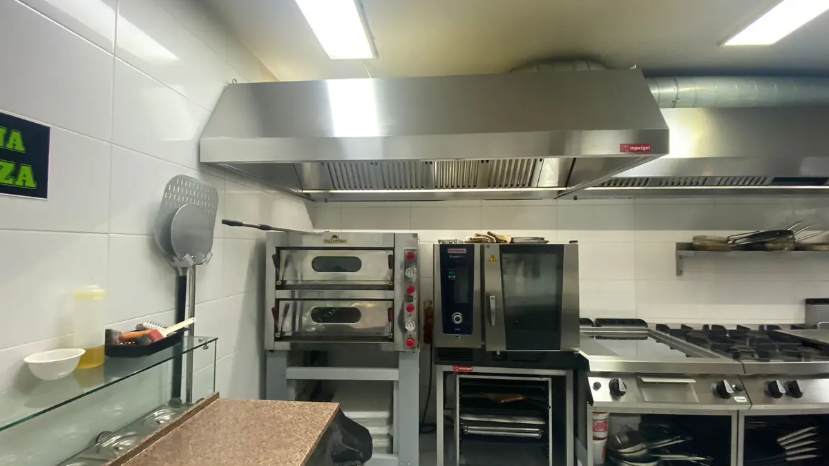 Hotă din inox deasupra unui cuptor de pizza și a unui cuptor mixt, racordată la tubulatură spiralată