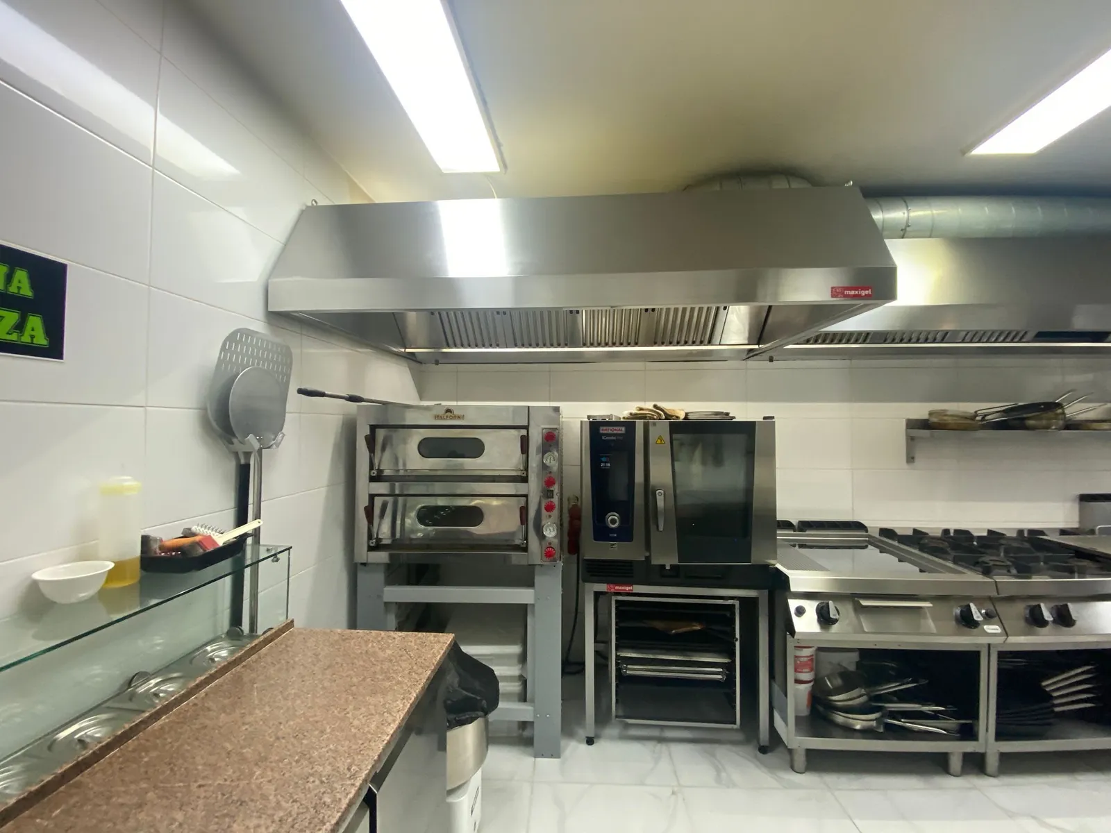 Hotă din inox deasupra cuptorului de pizza și a cuptorului mixt, racordată la tubulatură spiralată