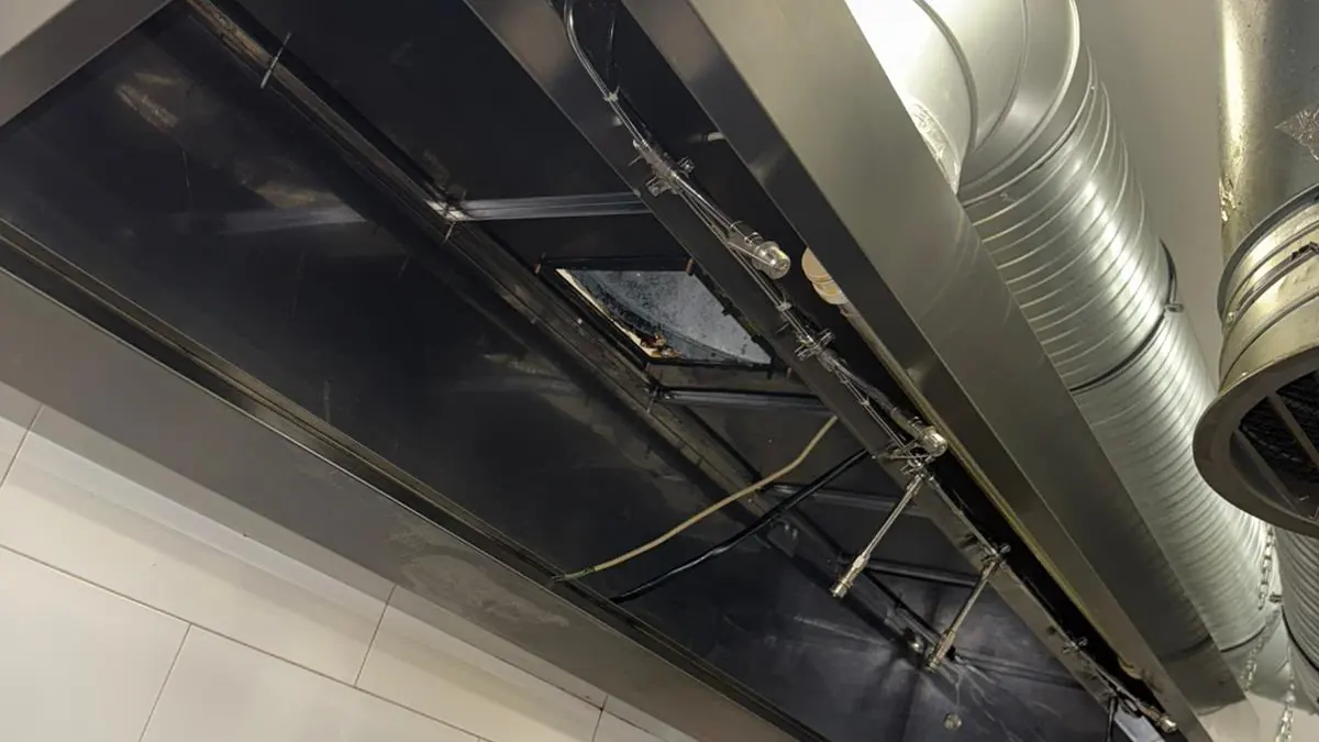 Hotă din inox cu filtrele scoase pentru curățare, sistem de stingere cu duze și tubulatură spiralată spre tavan