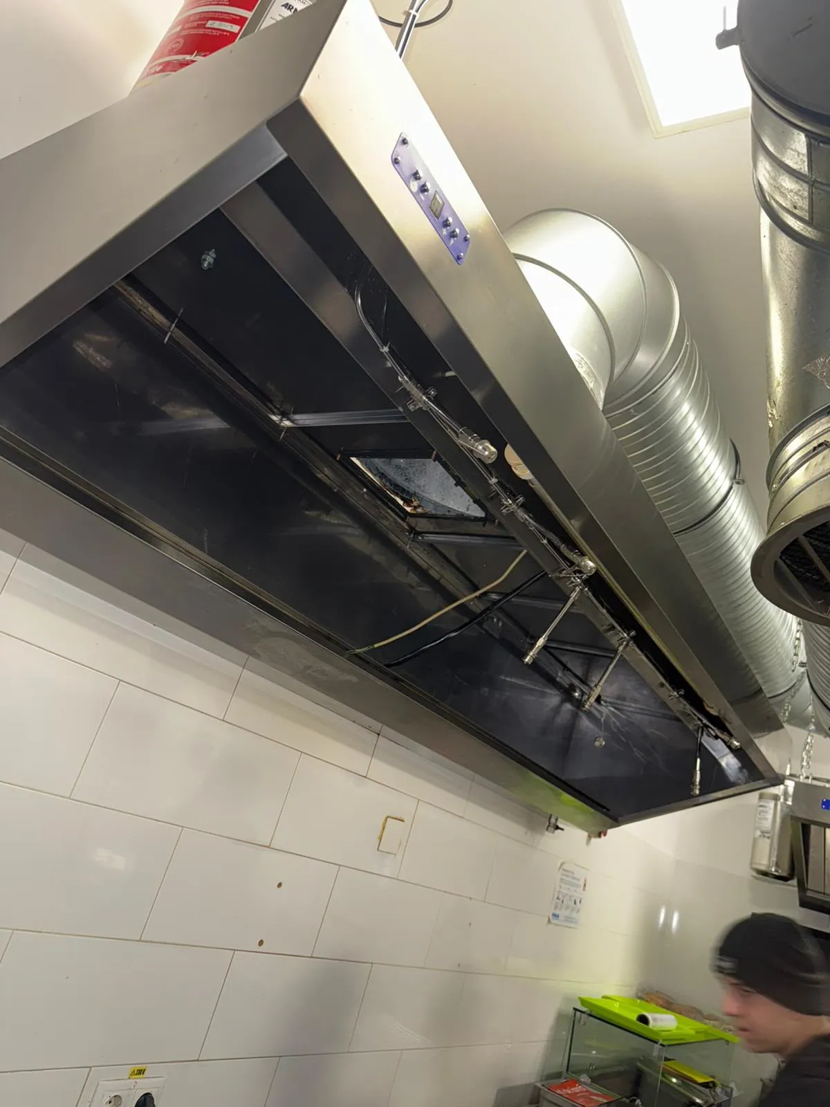 Hotă din inox cu filtrele scoase pentru curățare, cu duzele sistemului de stingere și tubulatura spiralată spre tavan