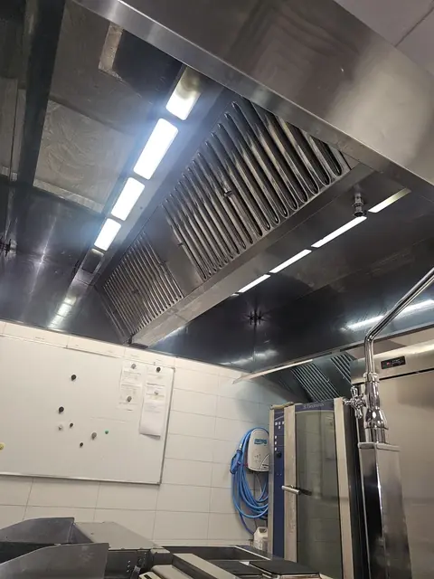 Hotă din inox văzută de dedesubt, cu filtre labirint curate și corpuri de iluminat LED integrate