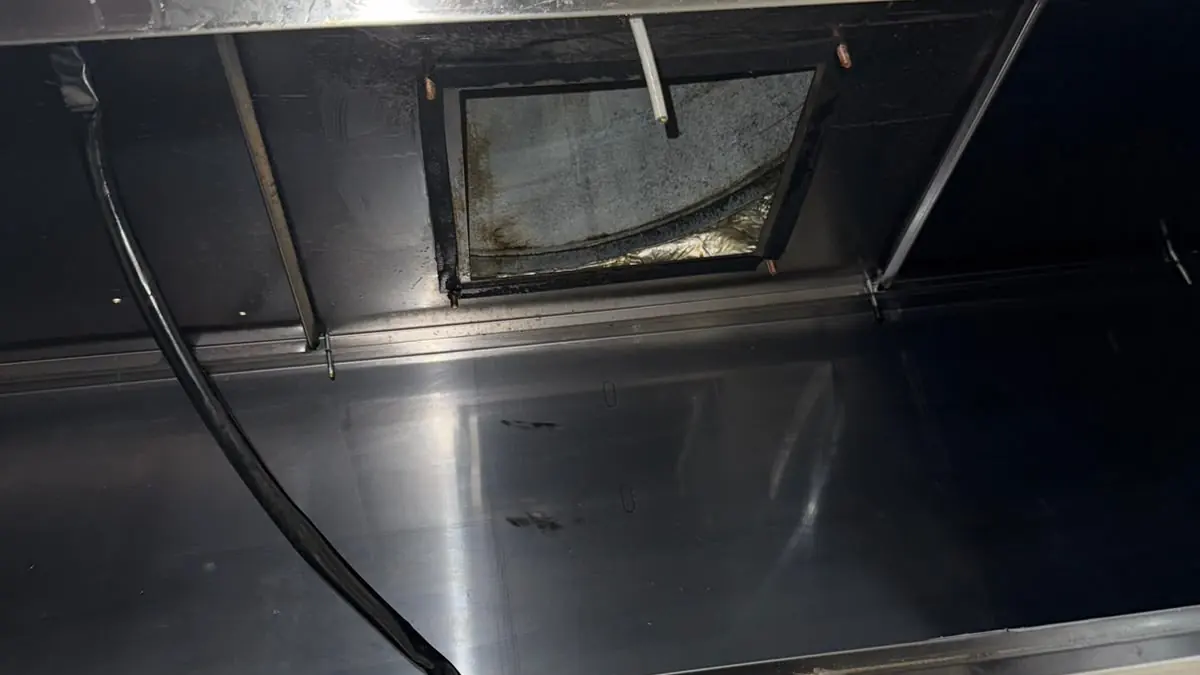 Interiorul unei hote din inox după curățare, cu gura de evacuare spre tubulatură și duza sistemului de stingere