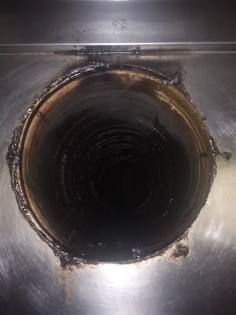 Racordul tubulaturii spiralate la hotă, cu depuneri negre și groase de grăsime pe margini și în interior