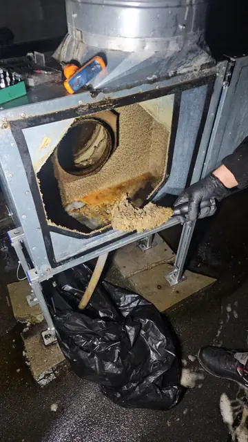 Răzuirea depunerilor groase de grăsime din carcasa ventilatorului, cu reziduurile strânse în sac de gunoi
