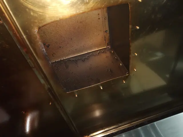 Racord rectangular de evacuare din interiorul hotei, cu depuneri lipicioase de grăsime maronie, înainte de curățare