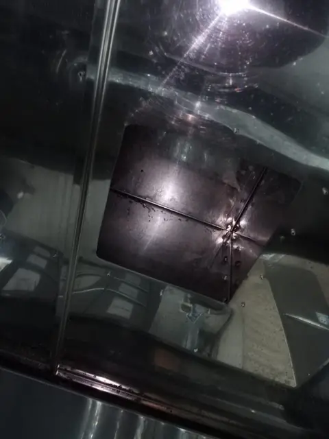 Racord rectangular de evacuare din interiorul hotei după degresare, cu inox lucios care reflectă lumina